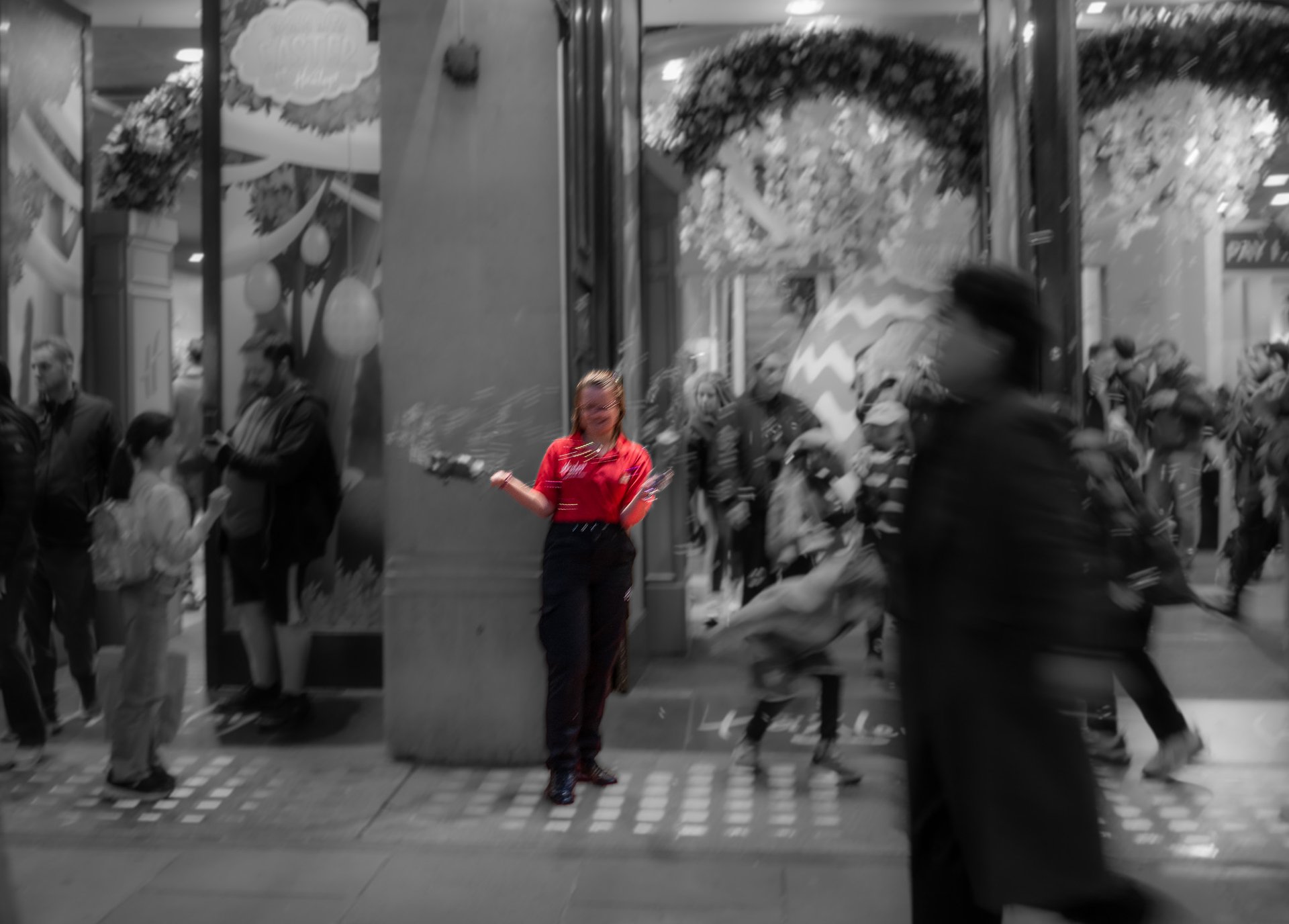 A performer in a red shirt entertains a crowd in a busy shopping area.